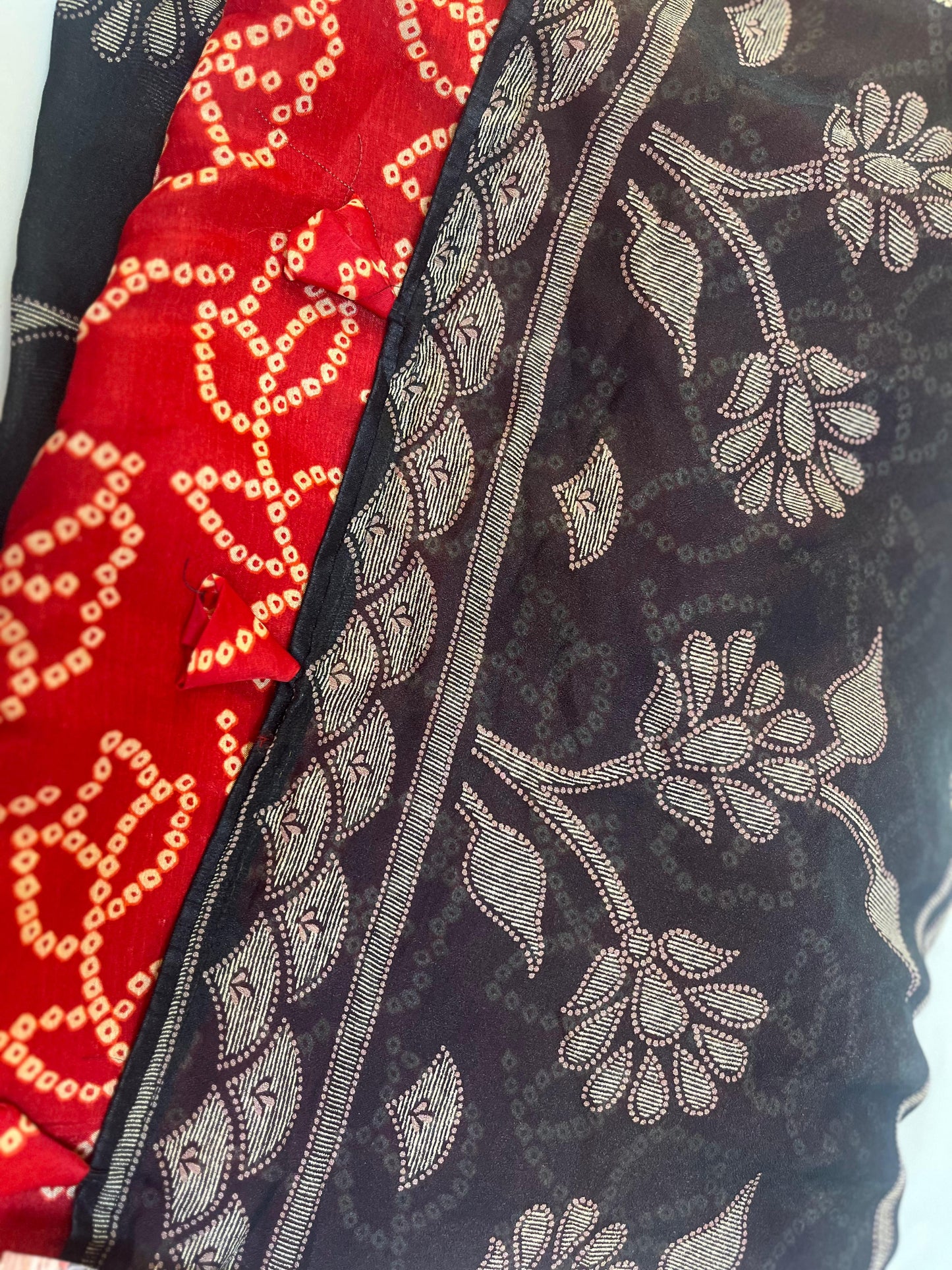 Close-up of patterned fabric with floral design on a navy-blue saree with red blouse