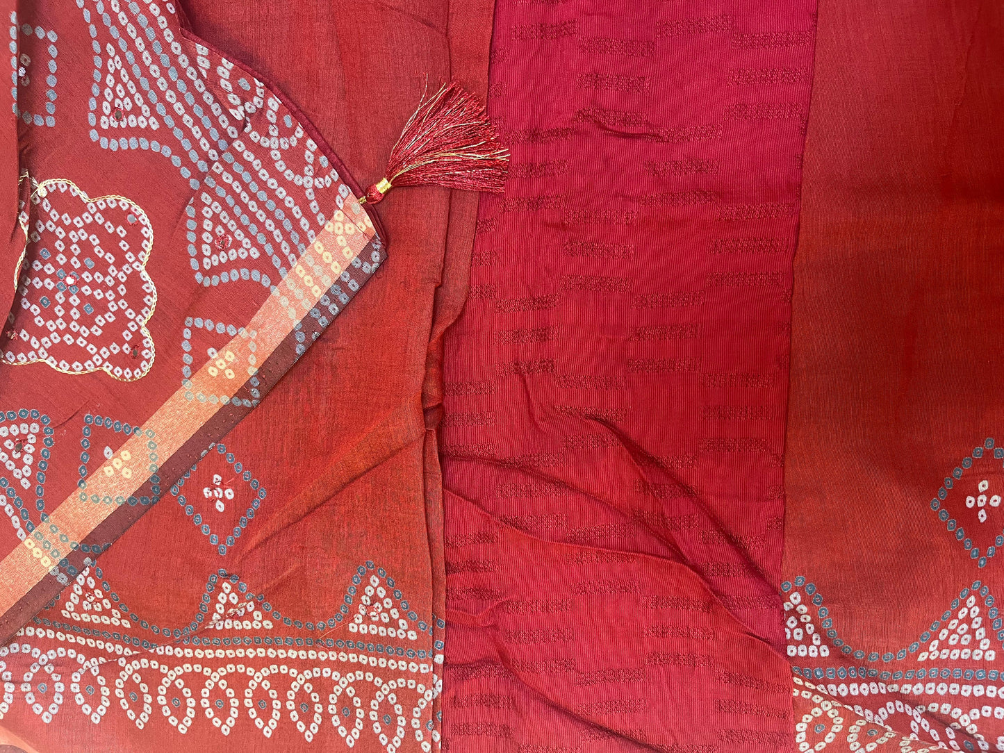 Red fabric with intricate white patterns and a tassel on a matching red background