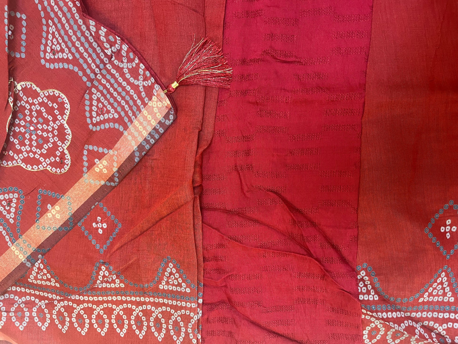 Red fabric with intricate white patterns and a tassel on a matching red background