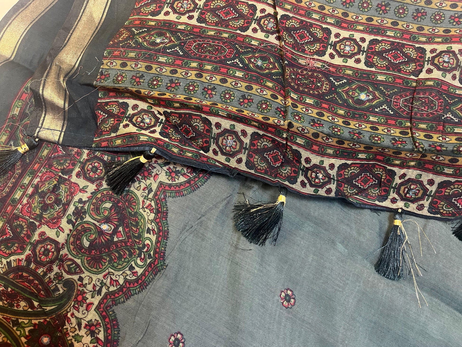Decorative fabric with intricate patterns and tassels on a textured background