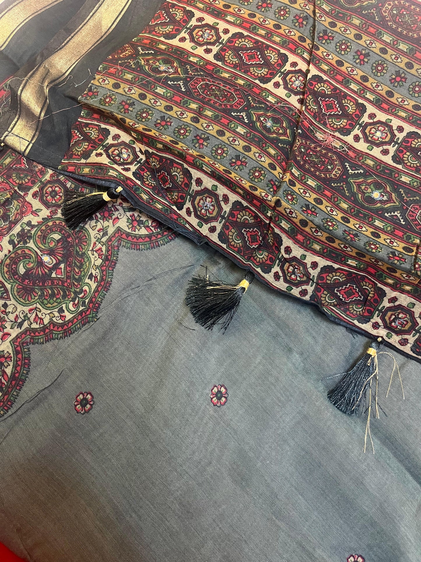 Decorative fabric with intricate patterns and tassels on a blue background