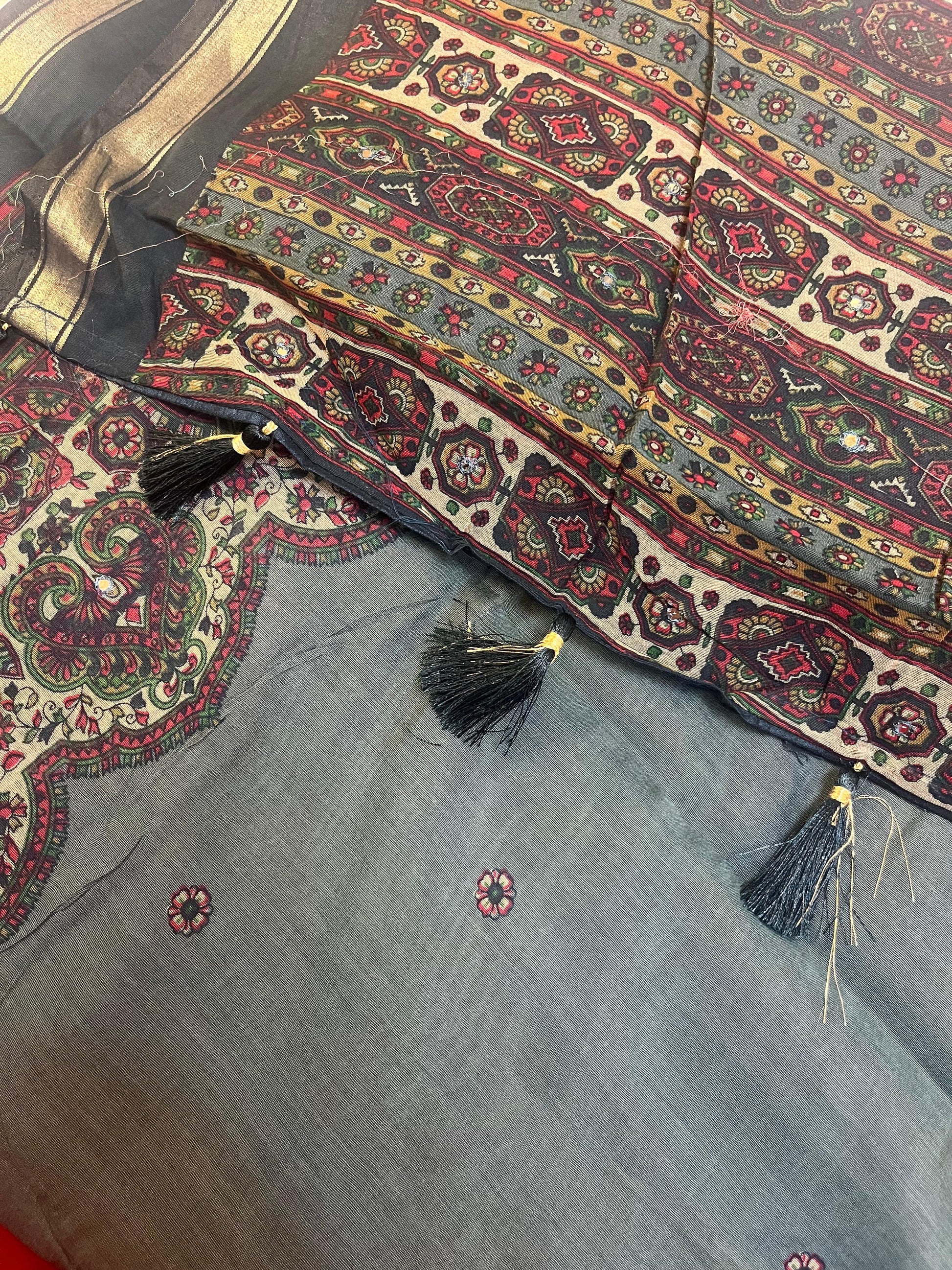 Decorative fabric with intricate patterns and tassels on a blue background